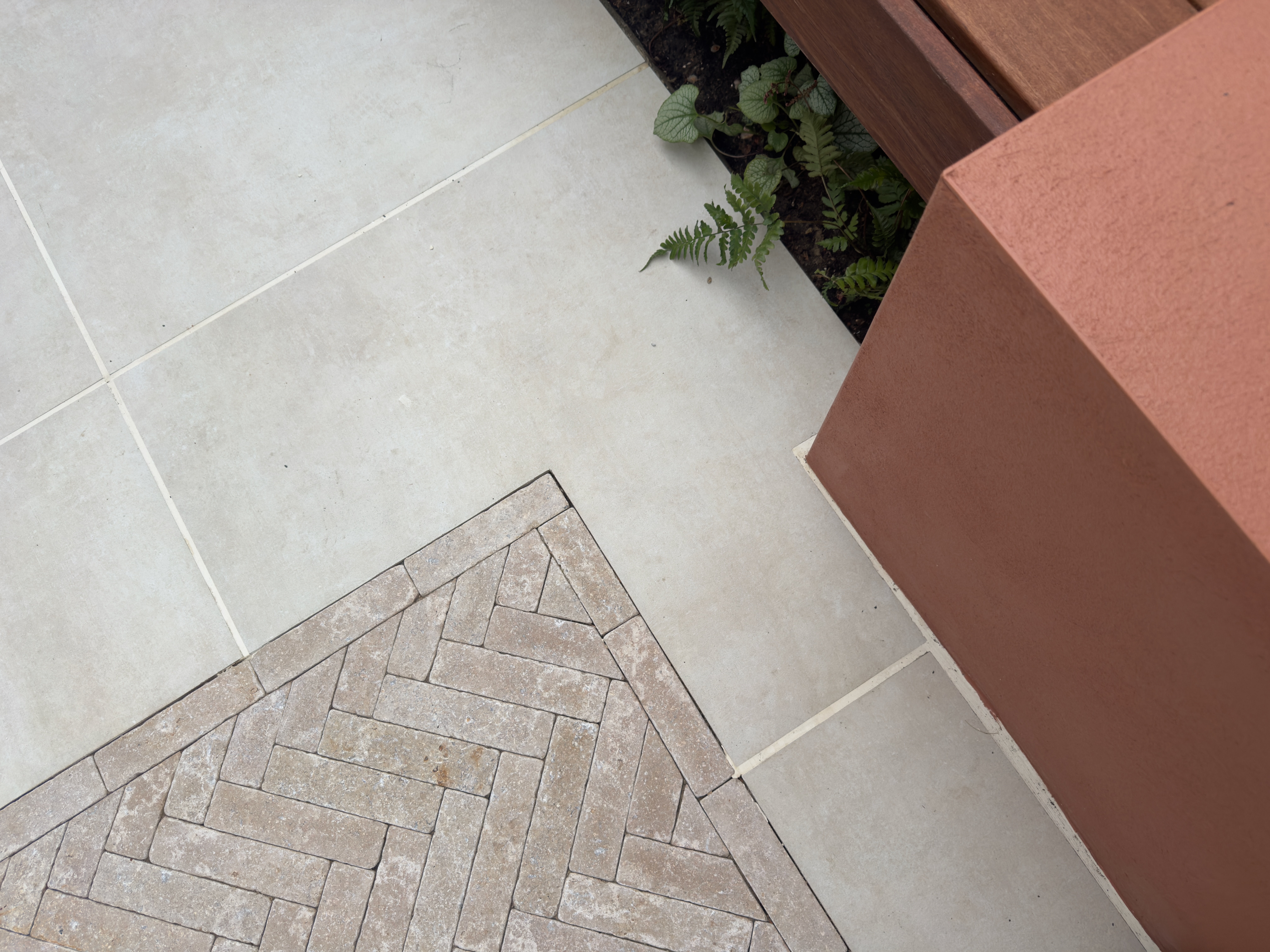 Large-format porcelain paving with inset herringbone brick detailing in a Seven Dials courtyard garden by Brunswick Landscapes